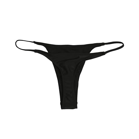 Bas de bikini tanga brésilien noir posé sur pierre claire avec un léger reflet d’eau.