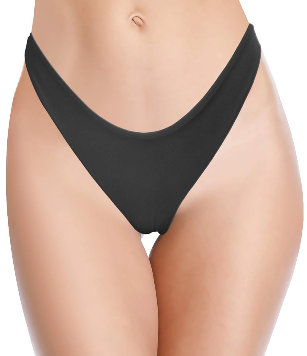 Bas de bikini string brésilien noir à taille basse, posé seul sur du lin ivoire près d’une pierre claire.